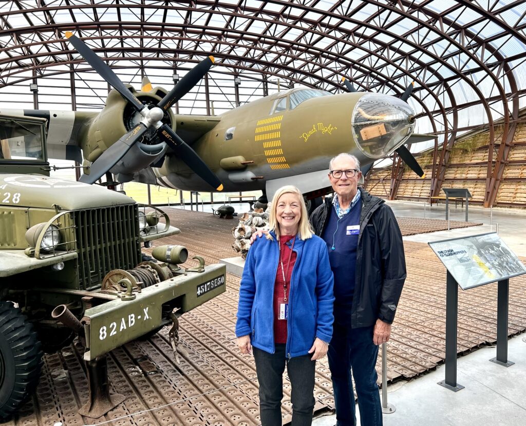 Hangar at Utah Beach Museum with a WWII plane in the background and 2 people