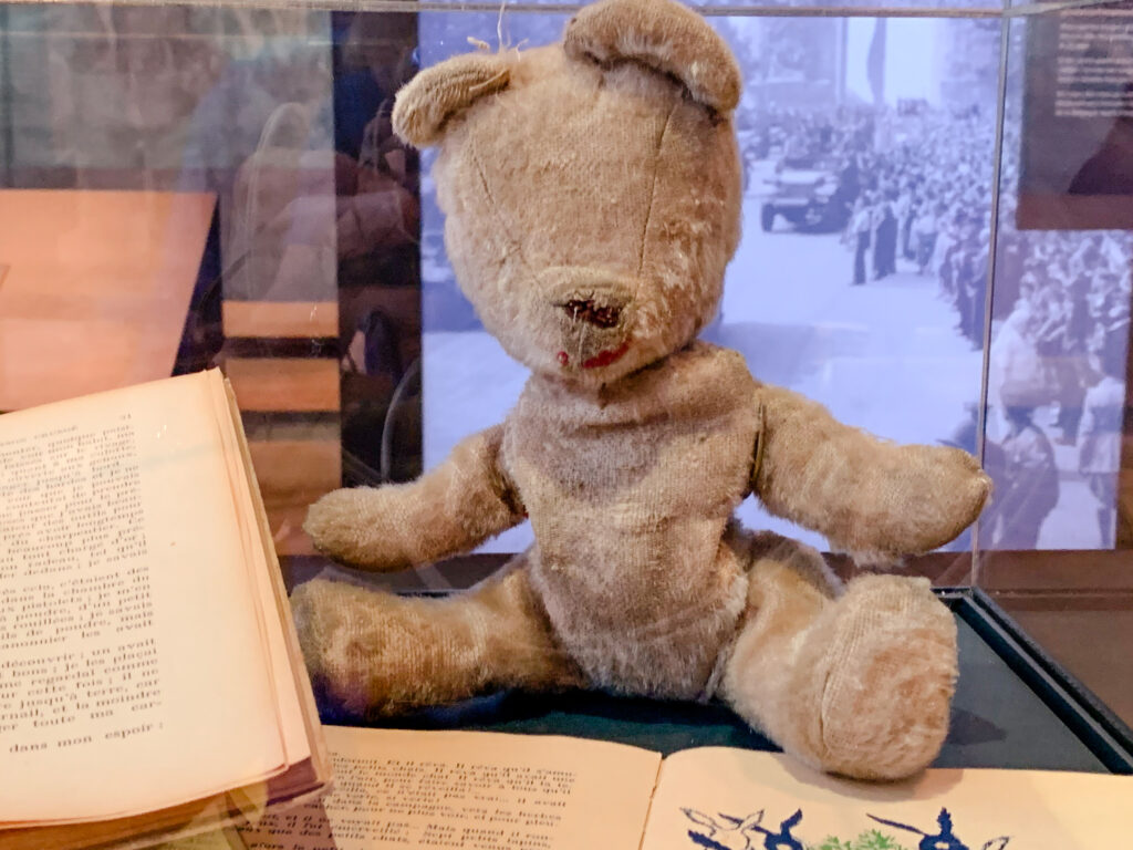 Teddy bear and personal effects of people on display at Overlord Museum at Omaha Beach